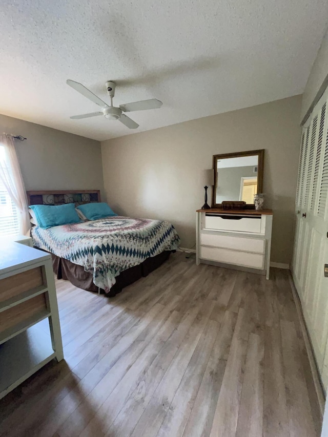 bedroom with a closet, a textured ceiling, a ceiling fan, and wood finished floors