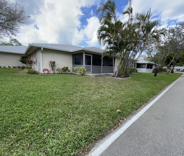 view of front of property featuring a sunroom, a front lawn, and stucco siding