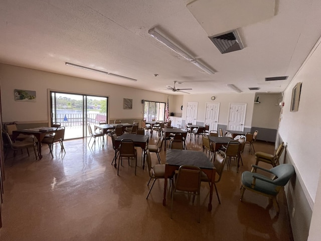 dining area with ceiling fan, concrete floors, a textured ceiling, and visible vents