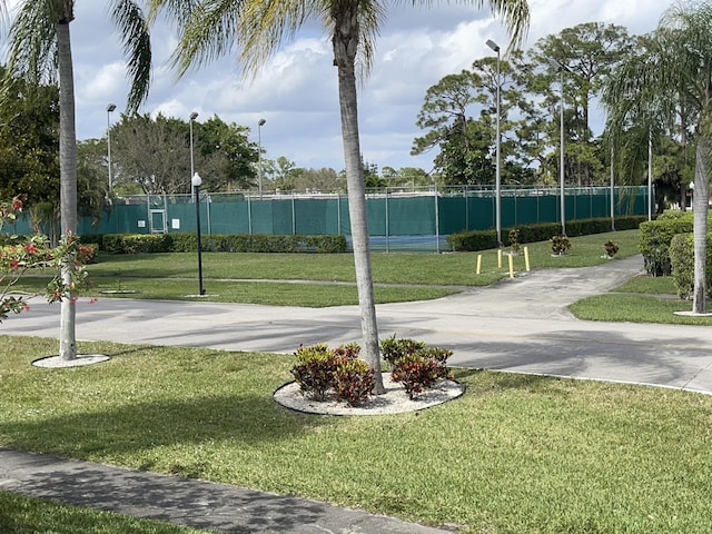 view of community featuring driveway, fence, and a lawn