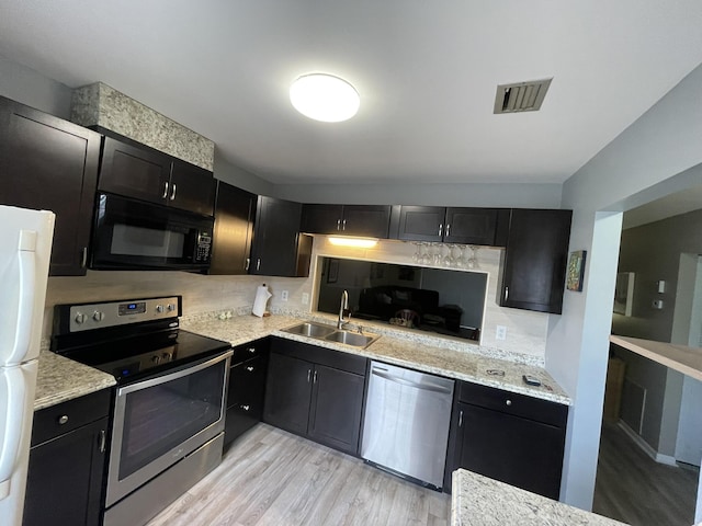 kitchen with visible vents, appliances with stainless steel finishes, dark cabinets, a sink, and backsplash