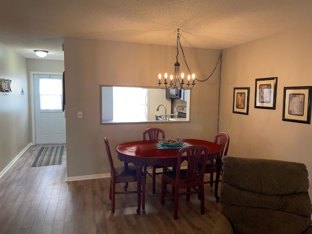 dining room with a textured ceiling, baseboards, and wood finished floors