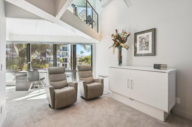 sitting room with carpet flooring, a ceiling fan, and a towering ceiling