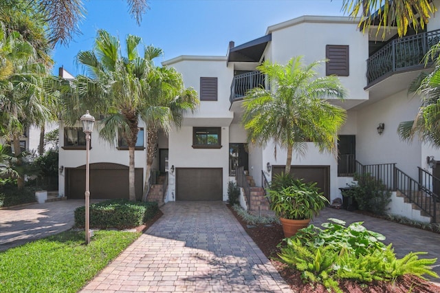 view of front of property featuring decorative driveway, an attached garage, and stucco siding