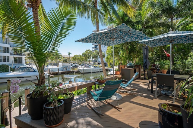 deck featuring outdoor dining area, a water view, and a dock