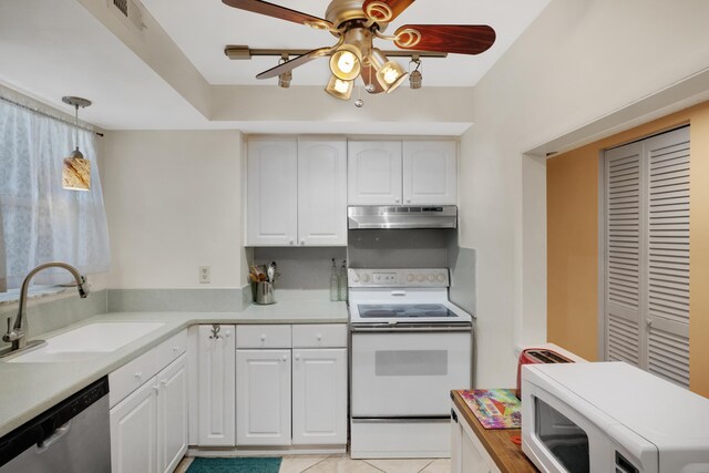 kitchen with white appliances, white cabinets, light countertops, under cabinet range hood, and a sink