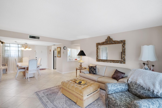 living room with light tile patterned floors, visible vents, a chandelier, and baseboards