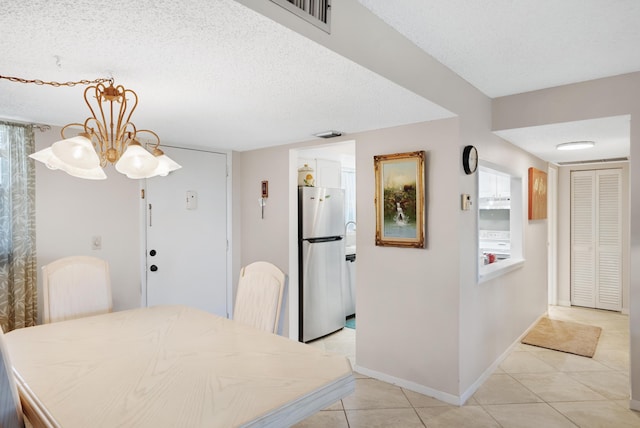 dining area with a textured ceiling, light tile patterned flooring, visible vents, and baseboards