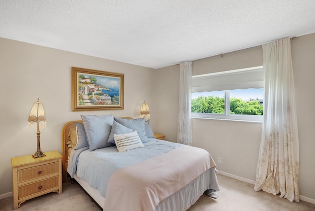 bedroom with light carpet, a textured ceiling, and baseboards