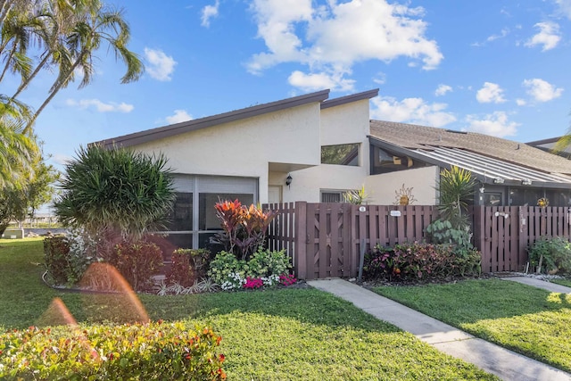 exterior space featuring a fenced front yard, a front yard, a gate, and stucco siding