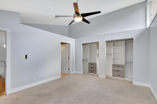 unfurnished bedroom featuring light carpet, vaulted ceiling, two closets, and baseboards