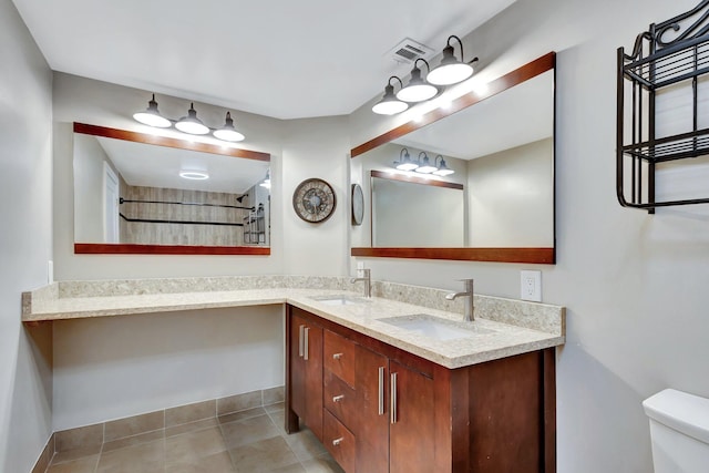 bathroom featuring visible vents, a sink, toilet, and double vanity