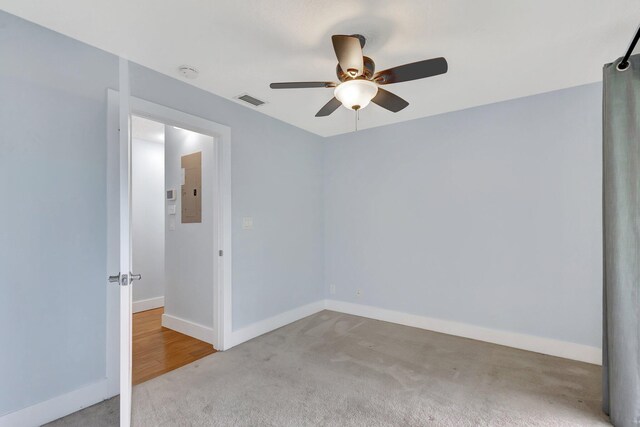 carpeted spare room with visible vents, ceiling fan, electric panel, and baseboards