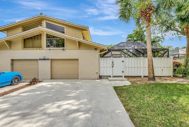 view of front of home featuring brick siding, concrete driveway, a gate, fence, and a lanai