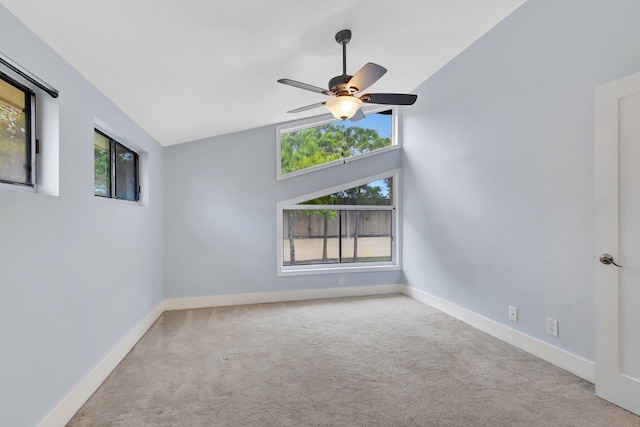 spare room featuring vaulted ceiling, carpet, a ceiling fan, and baseboards