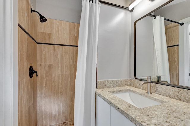 full bathroom featuring tiled shower and vanity