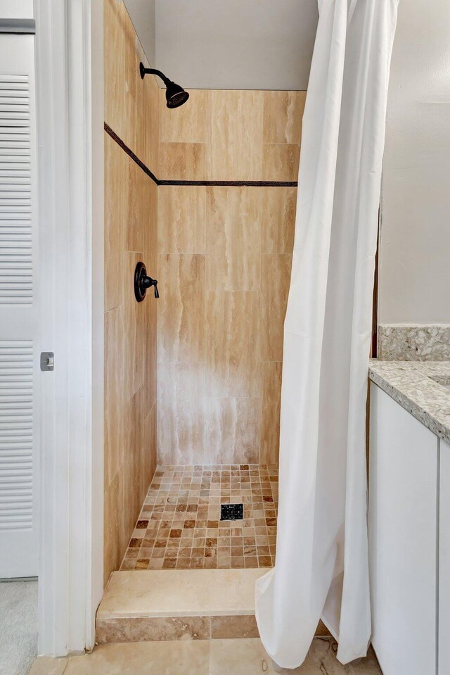 full bathroom featuring a tile shower and vanity