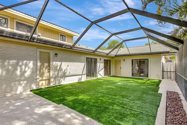 exterior space featuring glass enclosure, brick siding, a lawn, and a patio area