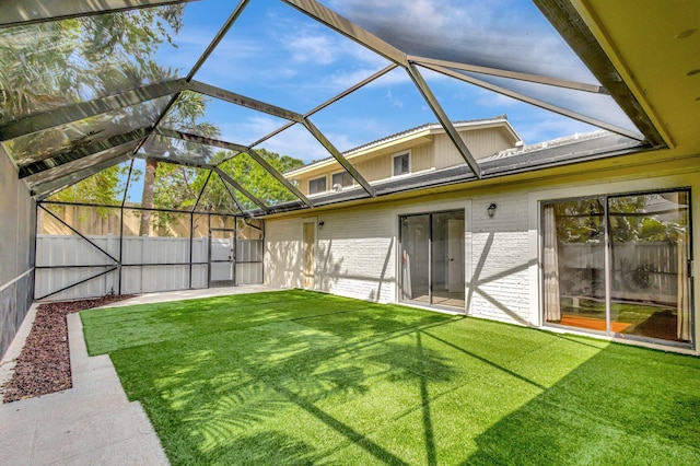 back of property featuring glass enclosure, a patio area, brick siding, and a lawn