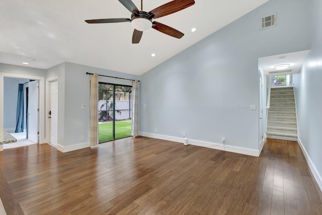 spare room with baseboards, visible vents, wood finished floors, stairs, and high vaulted ceiling