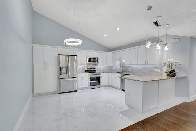 kitchen featuring a peninsula, visible vents, appliances with stainless steel finishes, light stone countertops, and decorative light fixtures