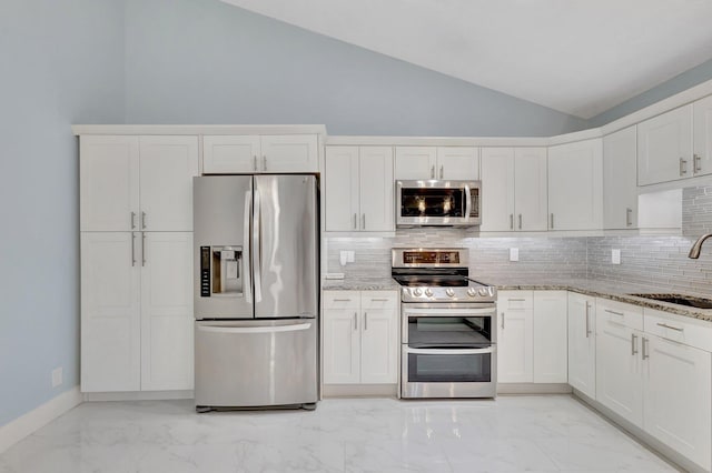 kitchen featuring light stone countertops, marble finish floor, vaulted ceiling, stainless steel appliances, and a sink