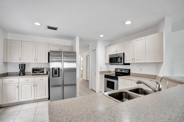 kitchen featuring light tile patterned floors, light countertops, visible vents, appliances with stainless steel finishes, and a sink