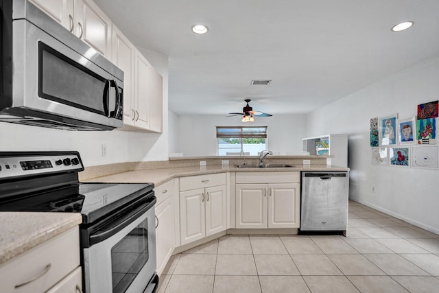 kitchen with visible vents, a peninsula, stainless steel appliances, white cabinetry, and a sink