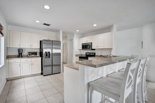 kitchen featuring a breakfast bar area, a peninsula, light tile patterned flooring, stainless steel appliances, and recessed lighting