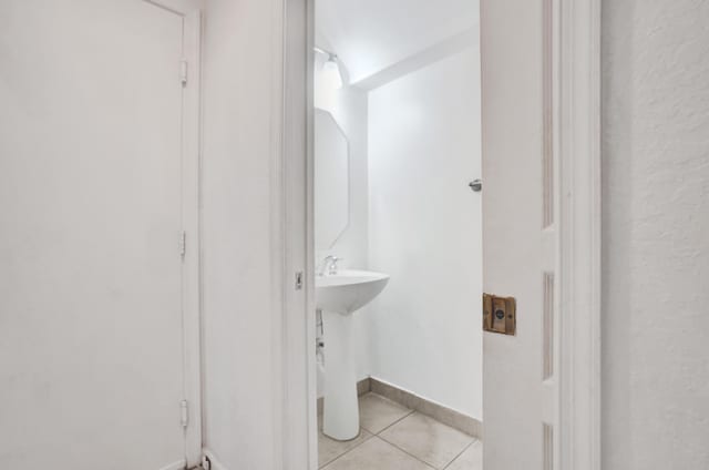 bathroom featuring tile patterned flooring, a sink, and baseboards