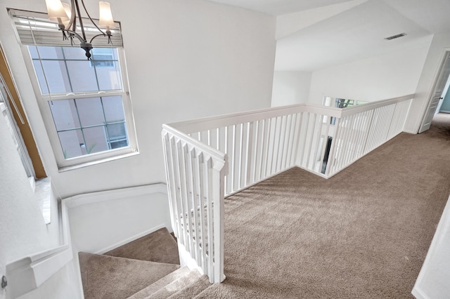 stairway featuring carpet floors, visible vents, and a chandelier