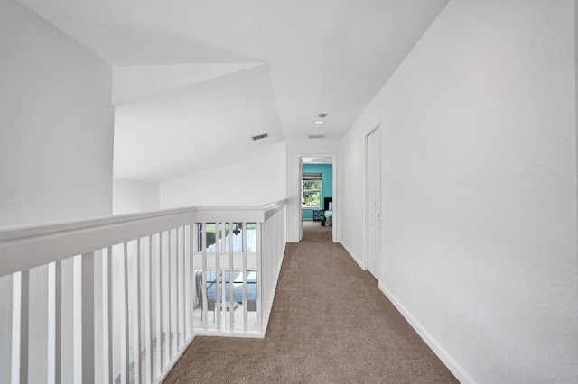 corridor featuring carpet, visible vents, lofted ceiling, and baseboards