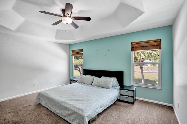 carpeted bedroom with a tray ceiling, ceiling fan, a textured ceiling, and baseboards