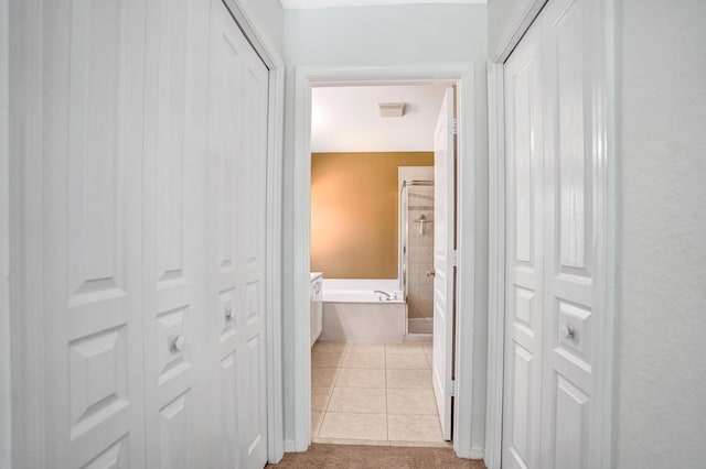 corridor featuring light tile patterned flooring and light carpet