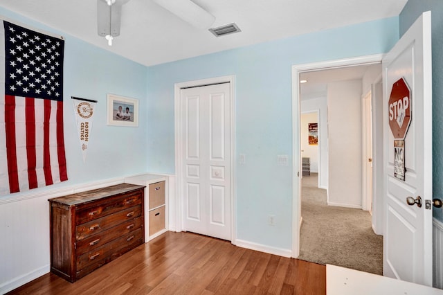 bedroom featuring baseboards, a closet, visible vents, and wood finished floors