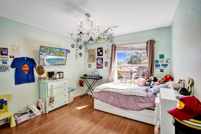 bedroom with wood finished floors and an inviting chandelier