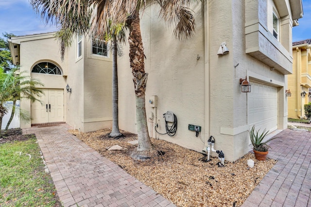 view of side of property featuring a garage and stucco siding