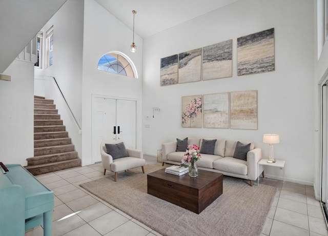 living room featuring stairway, tile patterned flooring, a towering ceiling, and baseboards