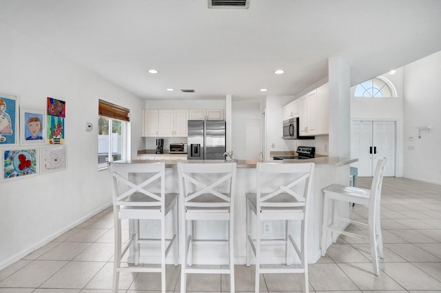 kitchen with a breakfast bar, light tile patterned floors, stainless steel appliances, and light countertops