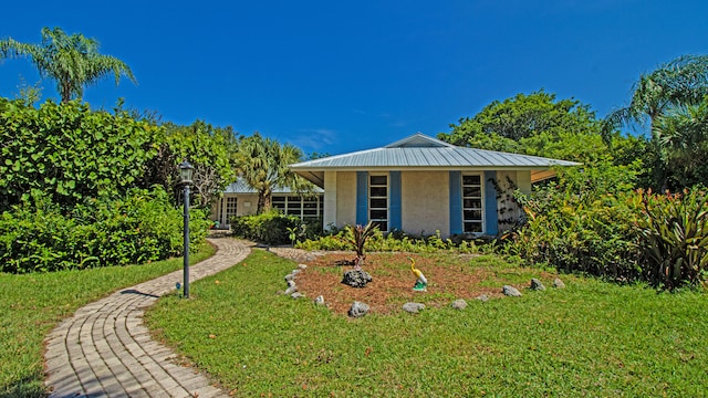 view of front facade featuring metal roof, a front lawn, and stucco siding