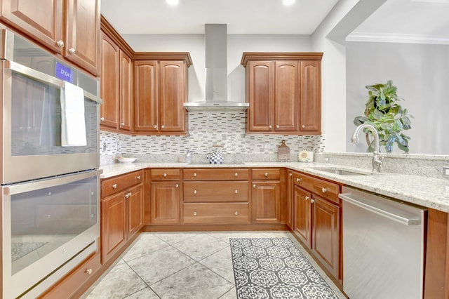 kitchen featuring a sink, wall chimney range hood, appliances with stainless steel finishes, light stone countertops, and tasteful backsplash