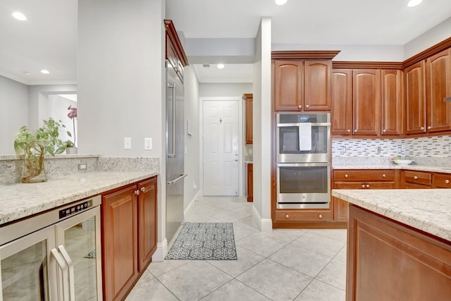 kitchen with decorative backsplash, wine cooler, light stone countertops, stainless steel appliances, and light tile patterned flooring