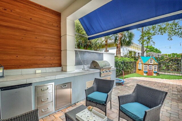 view of patio / terrace featuring an outbuilding, an outdoor kitchen, grilling area, and a fenced backyard