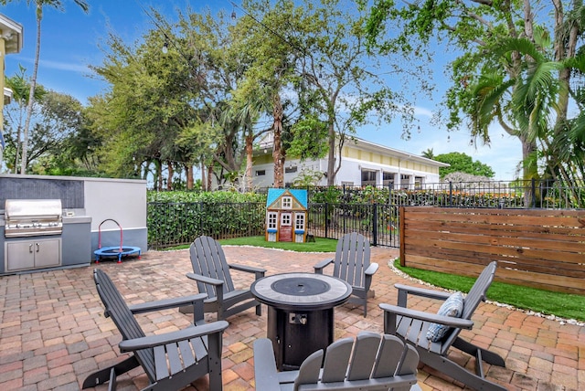 view of patio / terrace featuring exterior kitchen, a fenced backyard, a grill, and a fire pit