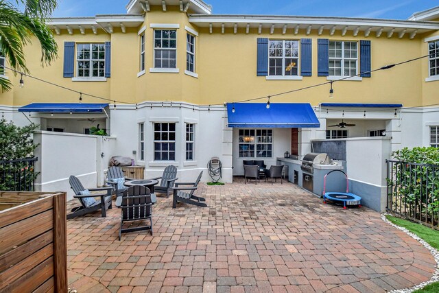 rear view of property with a patio area, fence, an outdoor kitchen, and stucco siding