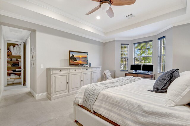 bedroom with a tray ceiling, light colored carpet, visible vents, ornamental molding, and baseboards