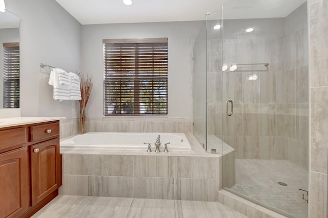 bathroom featuring a stall shower, vanity, and a bath