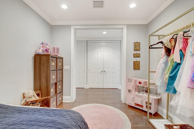 bedroom with visible vents, crown molding, baseboards, and wood finished floors