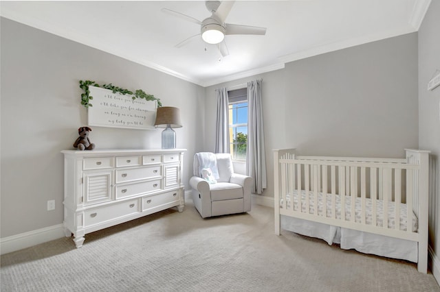 bedroom featuring baseboards, a nursery area, carpet, and crown molding