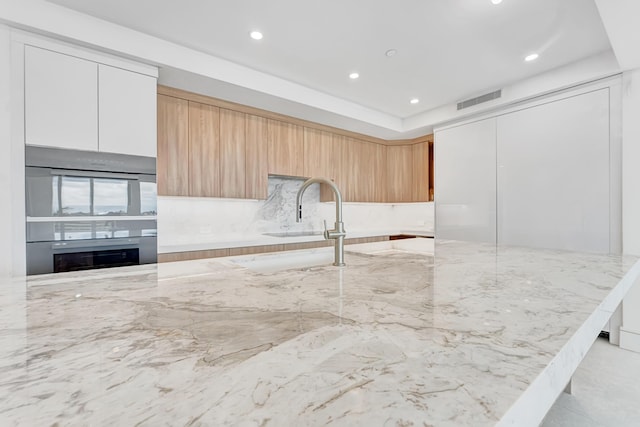 kitchen with modern cabinets, visible vents, light stone counters, and recessed lighting